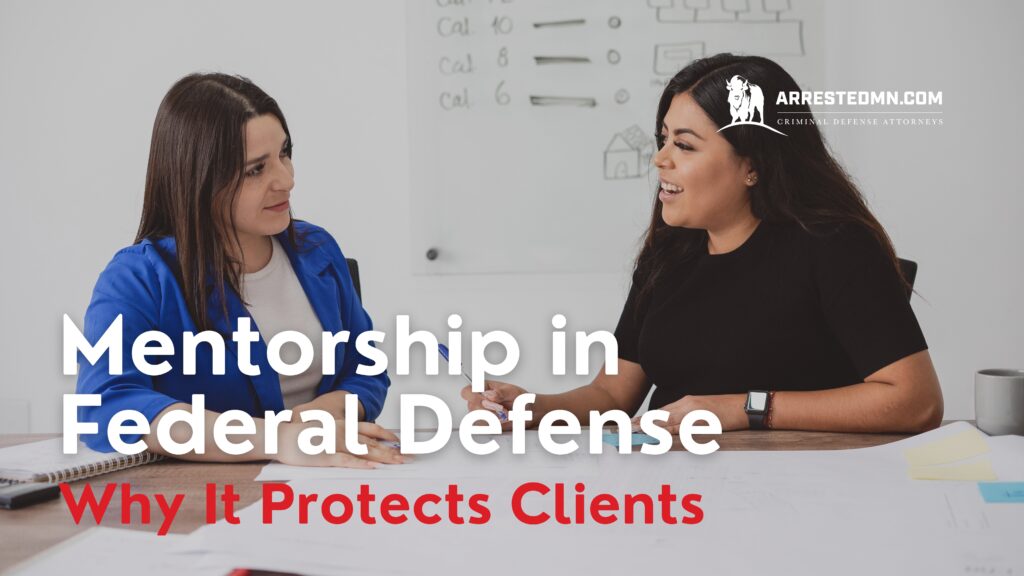 Two women sit at a table in a bright office, talking over documents, with ARRESTEDMN.COM branding in the corner.
